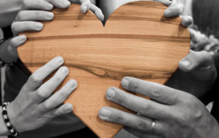 people holding a wooden heart